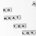 Scrabble tiles spelling 'Do What You Love' on a white background, encouraging creativity.