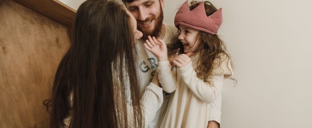 Happy family bonding indoors with parents and daughter sharing smiles and laughs.