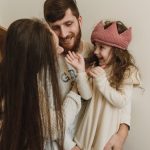 Happy family bonding indoors with parents and daughter sharing smiles and laughs.
